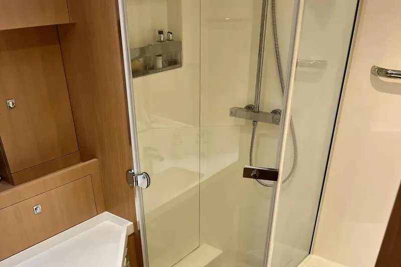  Yacht Photos Pics Modern shower cabin in 2016 Amel 64 yacht, featuring sleek glass doors and wooden accents.