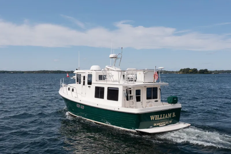 William B Yacht Photos Pics 2003 American Tug 34 cruising on a calm lake under a clear blue sky.