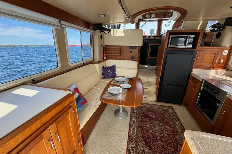 William B Yacht Photos Pics Interior of a 2003 American Tug 34 with dining area and kitchen, overlooking the water.