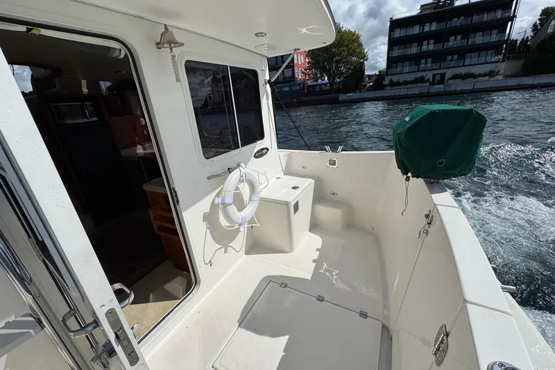 William B Yacht Photos Pics 2003 American Tug 34 boat deck with open cabin door, life ring, and water view.