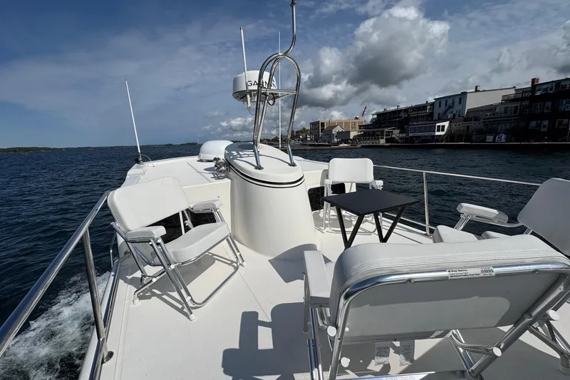 William B Yacht Photos Pics 2003 American Tug 34 boat deck with chairs and table, cruising near waterfront buildings.