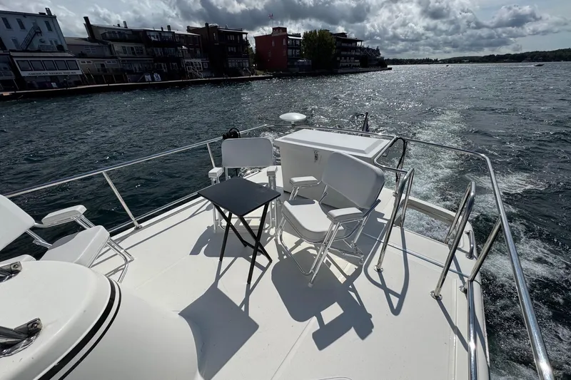 William B Yacht Photos Pics Deck view of 2003 American Tug 34, featuring chairs and table, cruising near waterfront buildings.