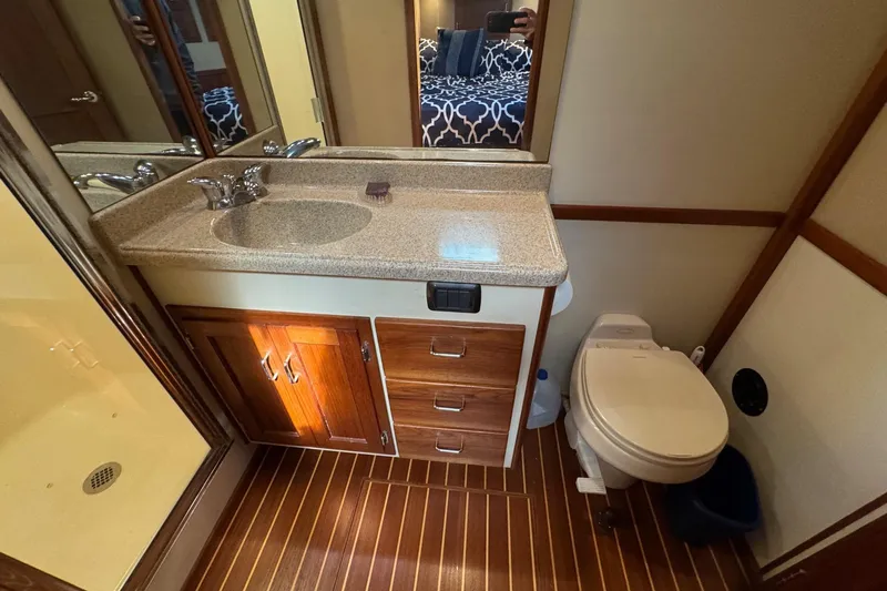William B Yacht Photos Pics 2003 American Tug 34 bathroom with wood cabinetry, sink, and toilet on striped flooring.