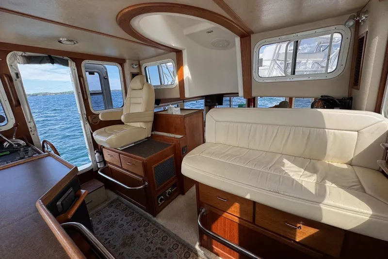 William B Yacht Photos Pics Interior of 2003 American Tug 34, featuring cream seating and wood accents, overlooking the ocean.