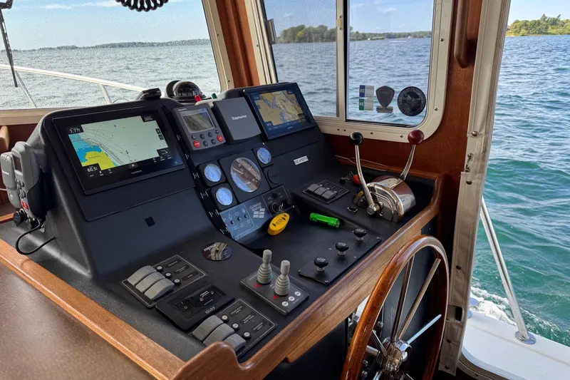 William B Yacht Photos Pics American Tug 34 (2003) helm with navigation equipment, steering wheel, and scenic water view.