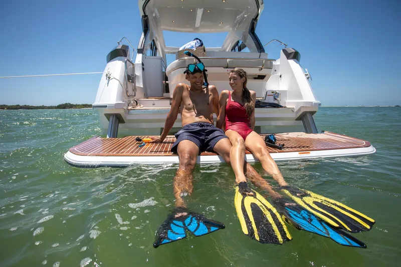 In Stock Yacht Photos Pics Couple relaxing on Beneteau Gran Turismo 41 yacht, wearing snorkeling gear, enjoying sunny day on the water.