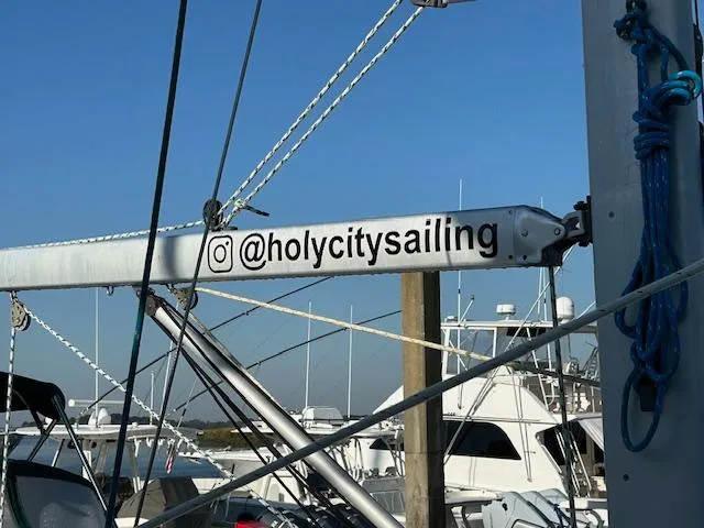Golden Handcuffs Yacht Photos Pics Beneteau 373 sailboat mast with "@holycitysailing" Instagram handle, marina background.