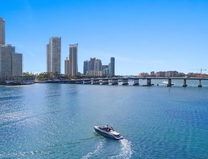 Mischief Yacht Photos Pics Boat cruising near city skyline and bridge, clear blue sky, Princess R35, 2021 model.