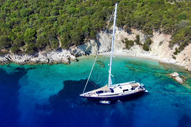 Unplugged Yacht Photos Pics Aerial view of 1993 Valdettaro 112 yacht anchored near a scenic, rocky coastline.