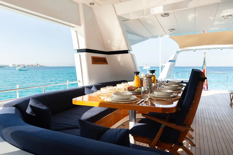 Unplugged Yacht Photos Pics Luxurious dining setup on Valdettaro 112 yacht, 1993, overlooking serene ocean waters.