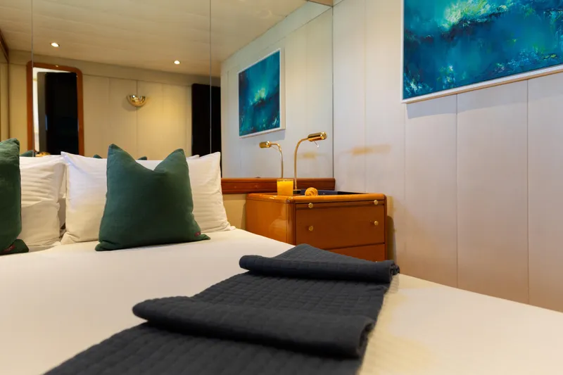 Unplugged Yacht Photos Pics Luxurious Valdettaro 112 yacht bedroom with elegant decor, green pillows, and ocean-themed artwork.