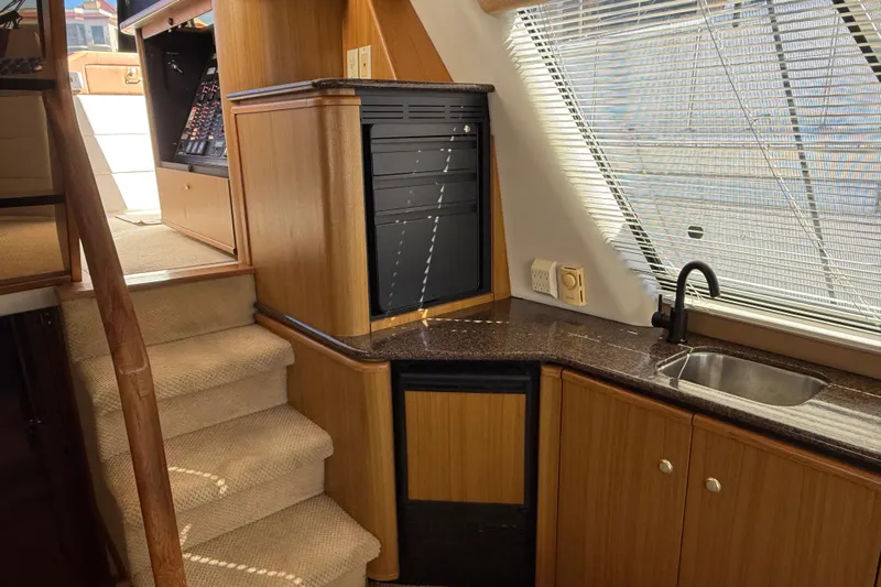  Yacht Photos Pics Interior of 2002 Bayliner 4788 Pilot House Motoryacht with stairs, kitchenette, and window blinds.