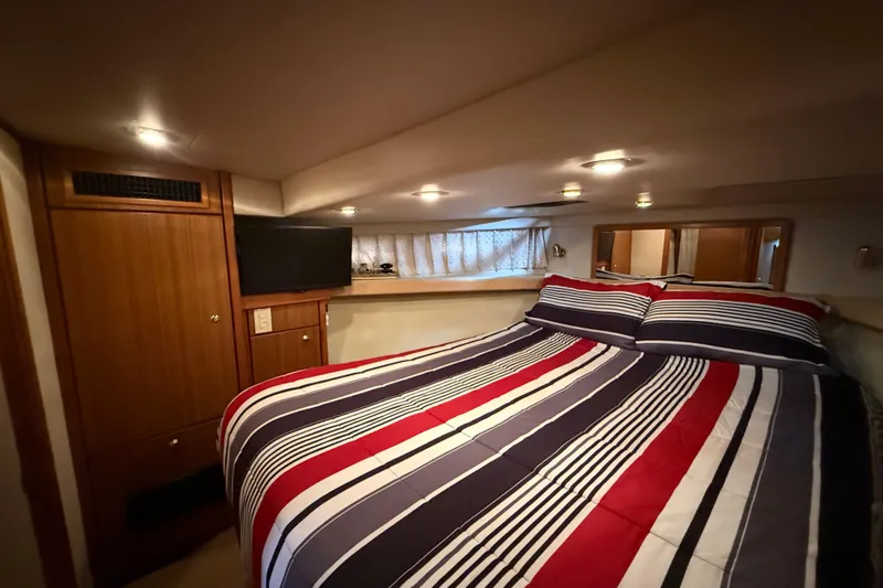  Yacht Photos Pics Cozy bedroom in 2002 Bayliner 4788 Pilot House Motoryacht with striped bedding and TV.