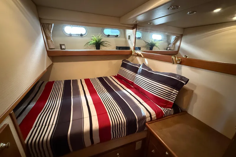  Yacht Photos Pics Cozy bedroom in 2002 Bayliner 4788 Pilot House Motoryacht with striped bedding and porthole windows.