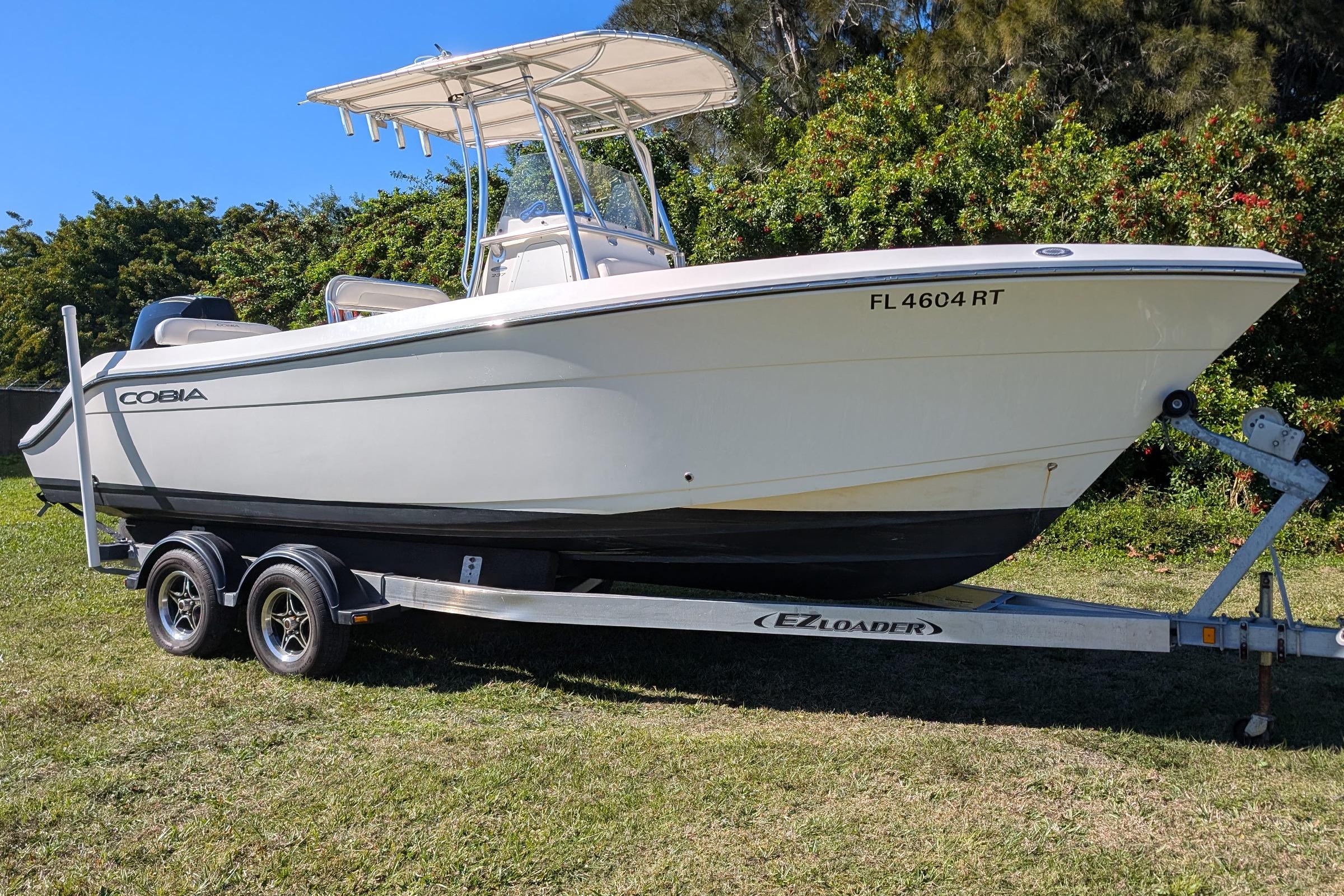 2019 Cobia 237 Center Console boat on trailer, parked on grass.