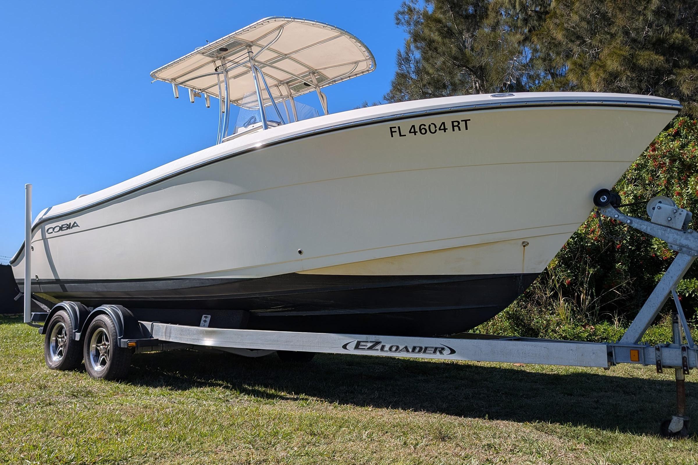 2019 Cobia 237 Center Console boat on EZ Loader trailer, parked on grass.