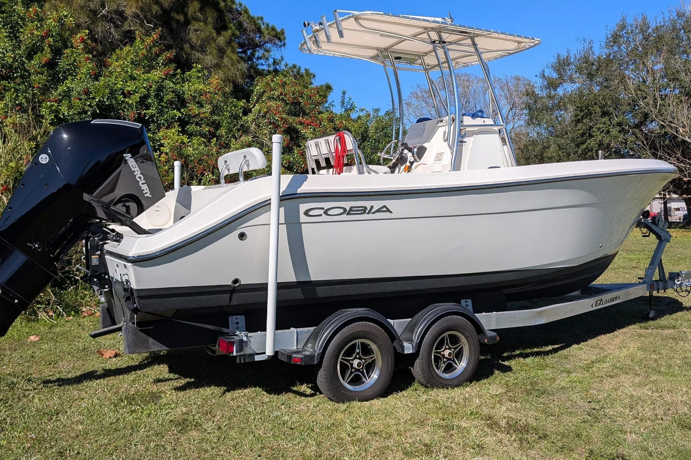 2019 Cobia 237 Center Console boat on trailer, parked on grass, with Mercury engine.