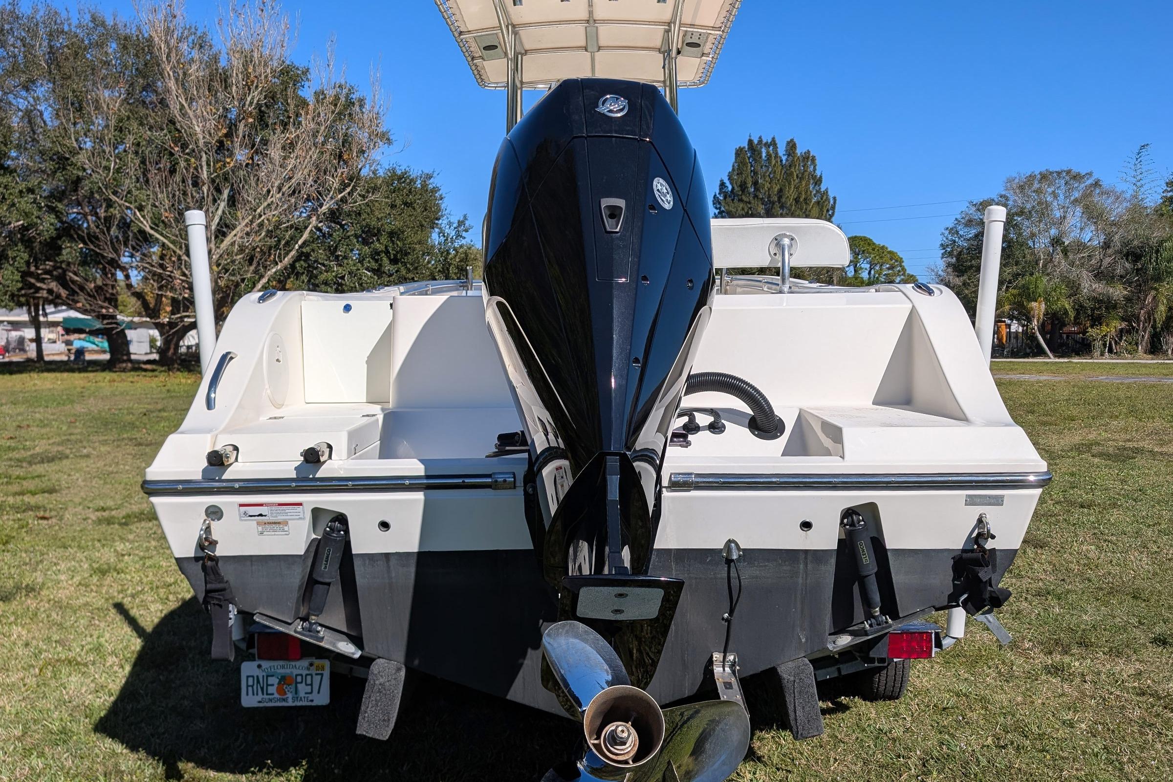 2019 Cobia 237 Center Console boat with powerful outboard motor on grassy area.