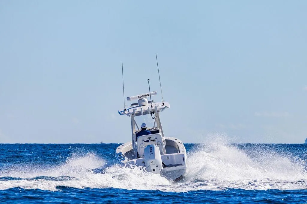 2024 Reef Runner 230 Open boat navigating ocean waves under clear blue sky.
