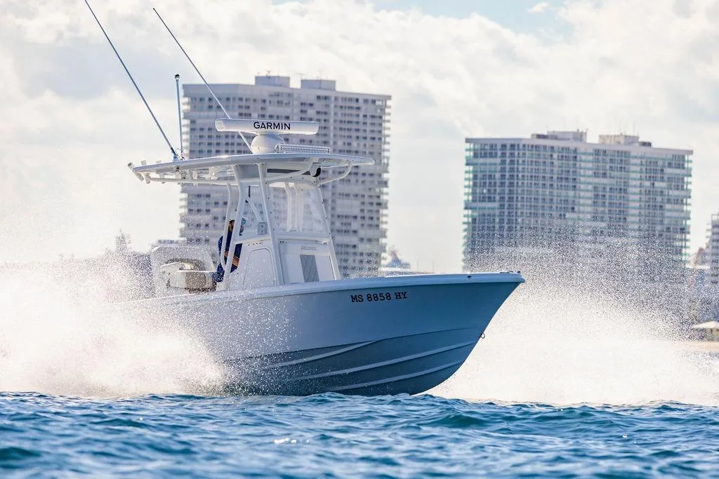 2024 Reef Runner 230 Open boat cruising on water with city skyline background.