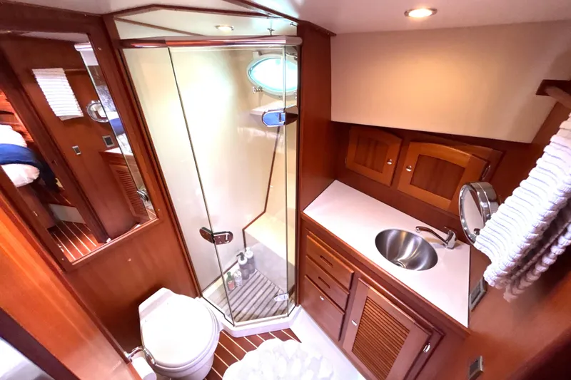 Flight Yacht Photos Pics Luxurious 2009 San Juan 48 yacht bathroom with glass shower, sink, and wooden cabinetry.