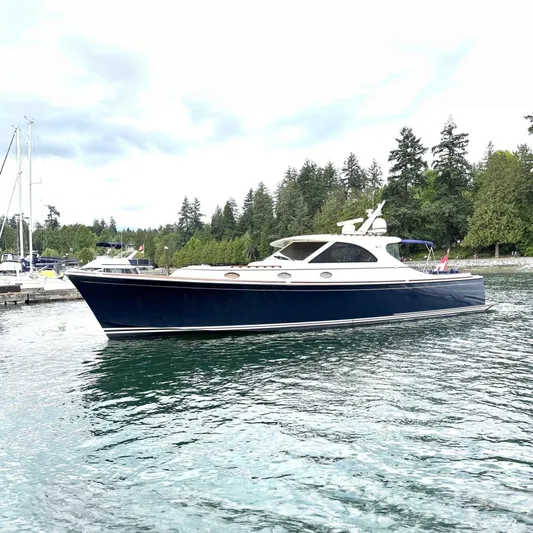 Flight Yacht Photos Pics 2009 San Juan 48 yacht on calm water, surrounded by lush greenery and other boats.