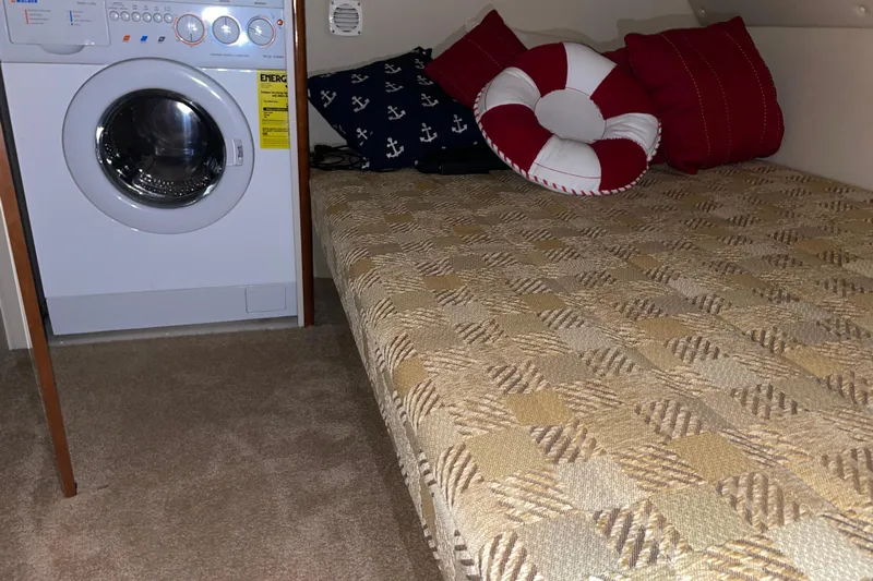  Yacht Photos Pics Laundry area and cozy bed with nautical-themed pillows on a 2004 Carver 460 Voyager.