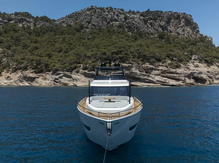 Orca I Yacht Photos Pics 2022 Cranchi Settantotto 78 yacht anchored in clear blue water near rocky coastline.
