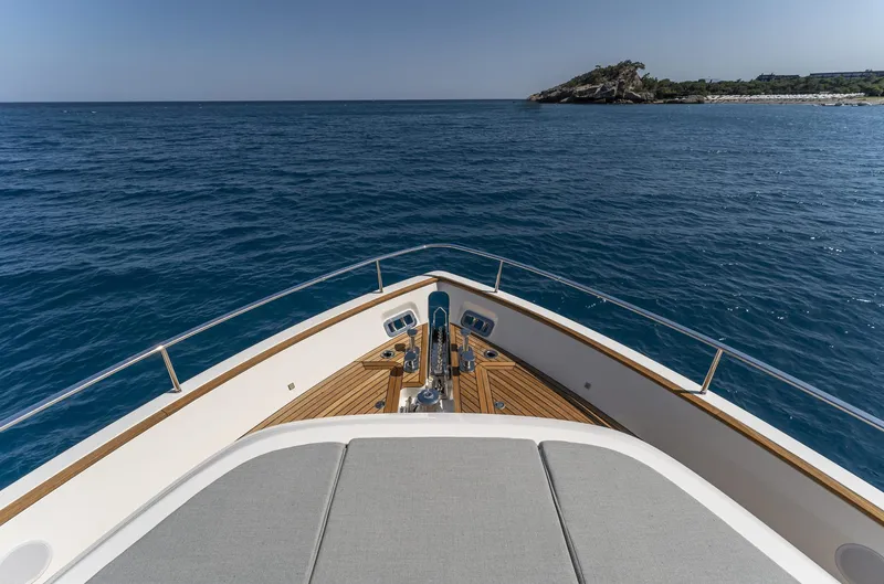 Orca I Yacht Photos Pics Bow view of 2022 Cranchi Settantotto 78 yacht on open sea near rocky coastline.