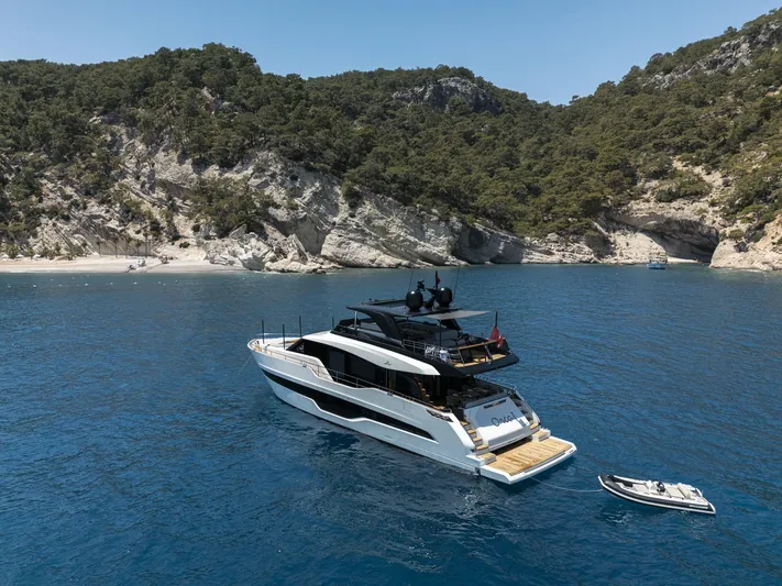 Orca I Yacht Photos Pics 2022 Cranchi Settantotto 78 yacht anchored in a scenic bay with lush cliffs.