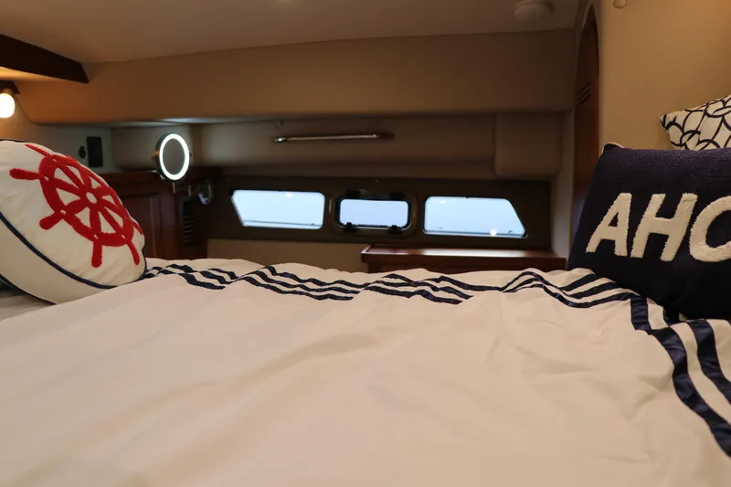  Yacht Photos Pics Cozy cabin interior of 2026 Aspen C120 Flybridge with nautical-themed pillows and porthole windows.