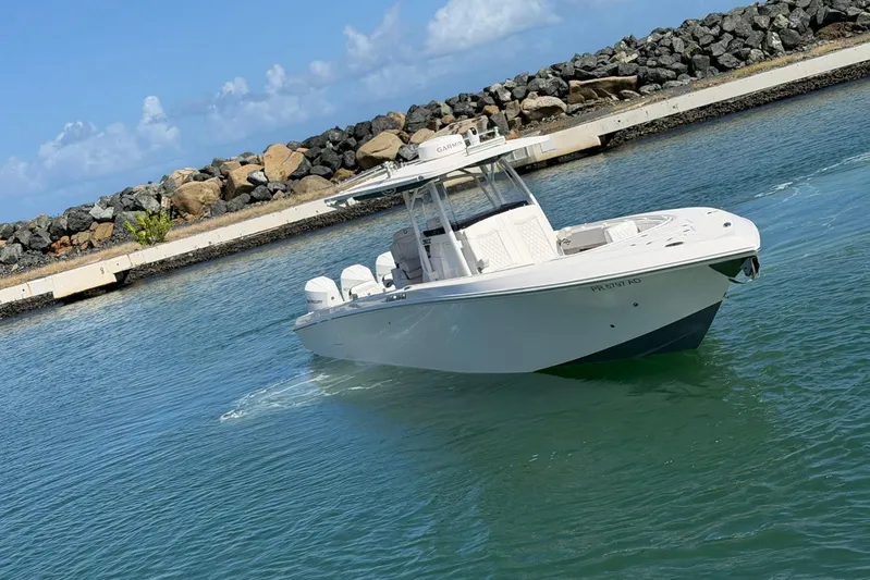  Yacht Photos Pics 2023 Fountain 34 Center Console boat on water near rocky shoreline.