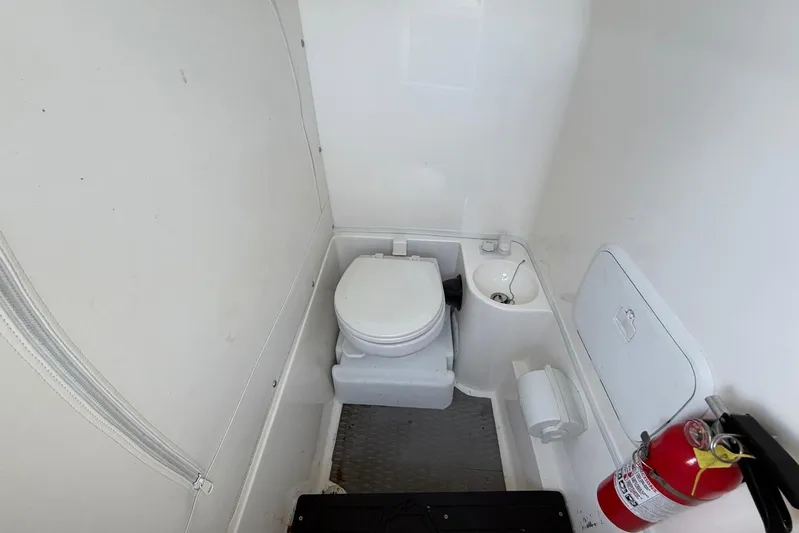  Yacht Photos Pics 2023 Fountain 34 Center Console boat bathroom with toilet and fire extinguisher.