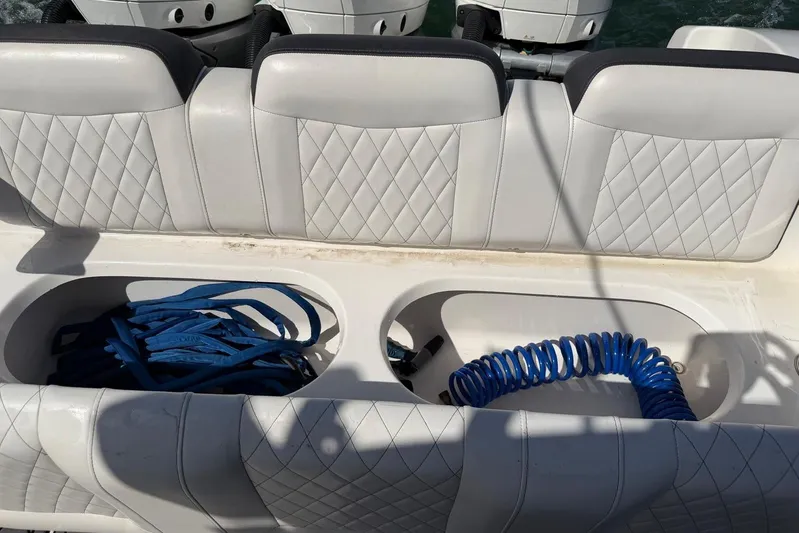  Yacht Photos Pics 2023 Fountain 34 Center Console boat seating with storage compartments and coiled blue hose.