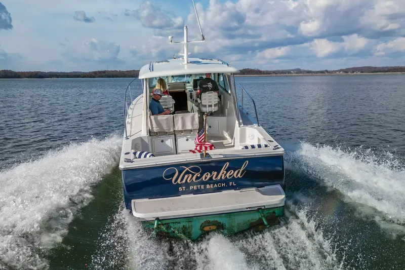  Yacht Photos Pics 2008 Back Cove 29 boat "Uncorked" cruising on a lake under a cloudy sky.