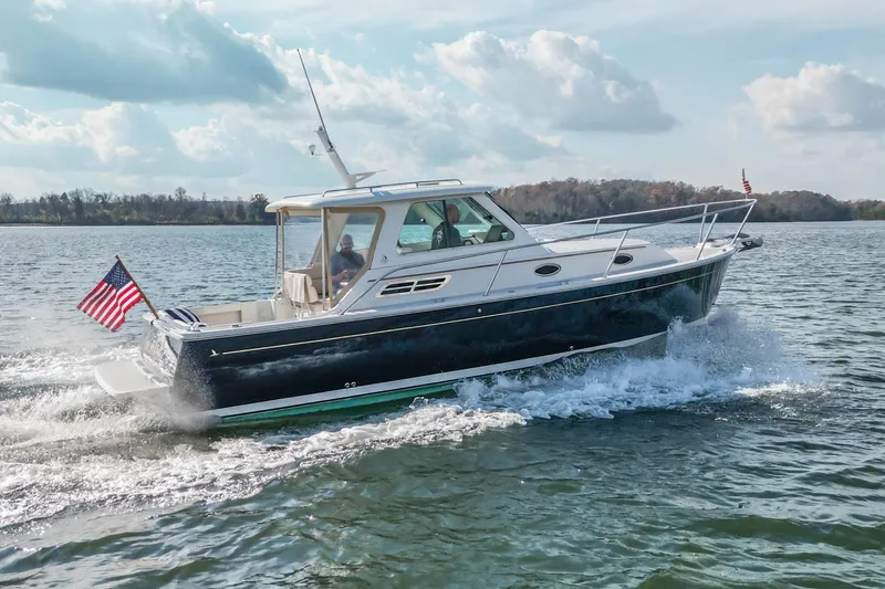  Yacht Photos Pics 2008 Back Cove 29 boat cruising on a lake with American flag, under a partly cloudy sky.