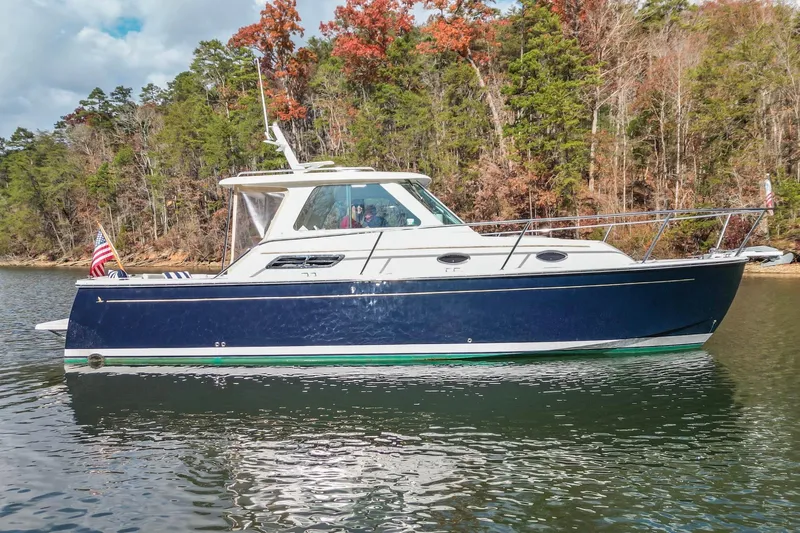  Yacht Photos Pics 2008 Back Cove 29 boat on a calm lake with forested shoreline.