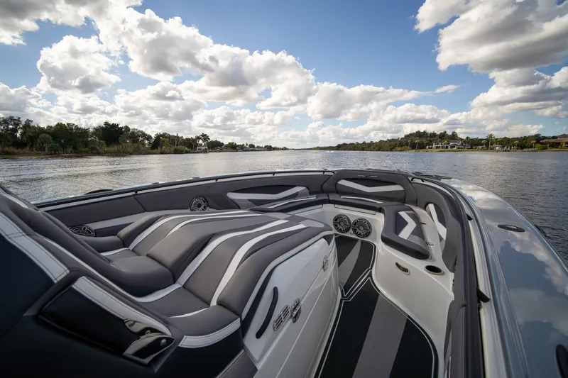  Yacht Photos Pics Luxurious MTI V42 boat interior with sleek seating, cruising on a scenic lake under a cloudy sky.