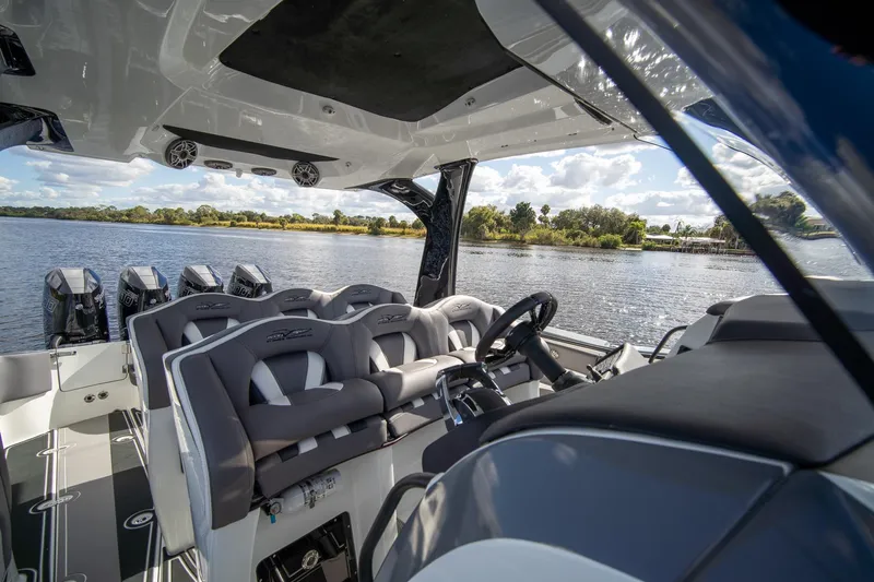  Yacht Photos Pics Interior view of 2020 MTI V42 boat with luxurious seating and multiple engines on a scenic lake.