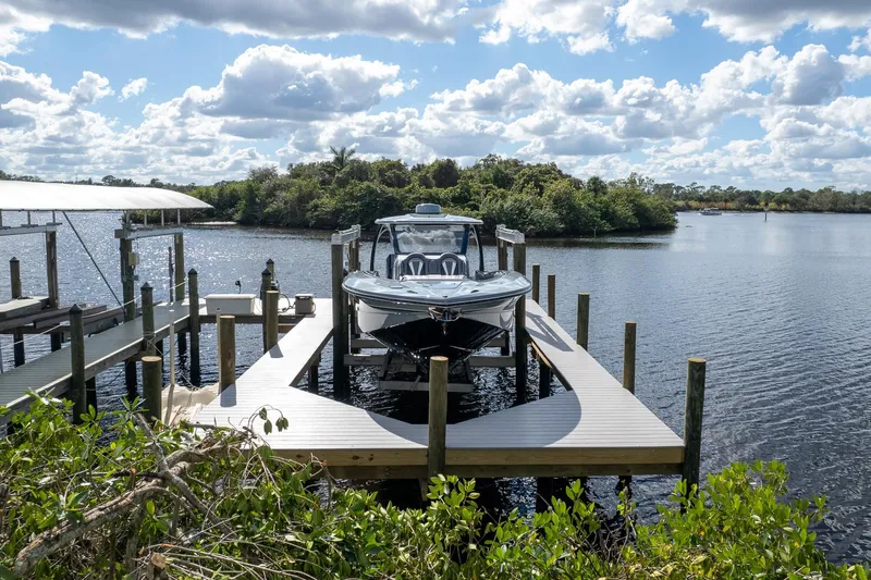  Yacht Photos Pics 2020 MTI V42 boat docked on a serene lake under a partly cloudy sky.