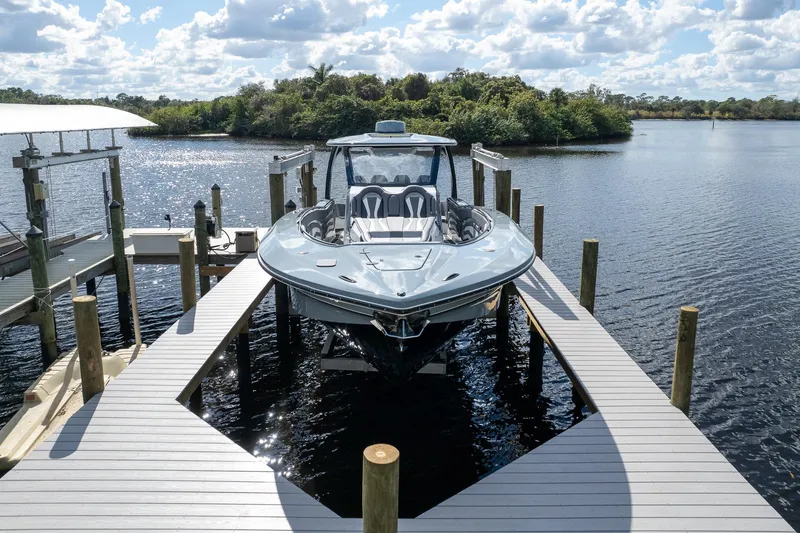  Yacht Photos Pics MTI V42 2020 boat docked on a sunny day, surrounded by calm water and lush greenery.