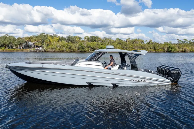  Yacht Photos Pics 2020 MTI V42 boat cruising on a calm river under a partly cloudy sky.