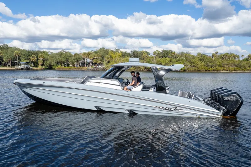  Yacht Photos Pics 2020 MTI V42 boat cruising on a scenic river under a partly cloudy sky.