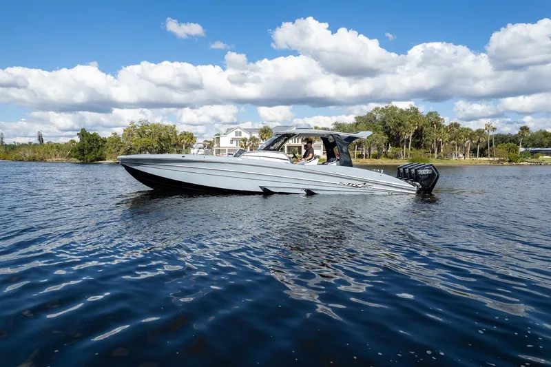  Yacht Photos Pics 2020 MTI V42 boat cruising on a scenic lake under a blue sky.