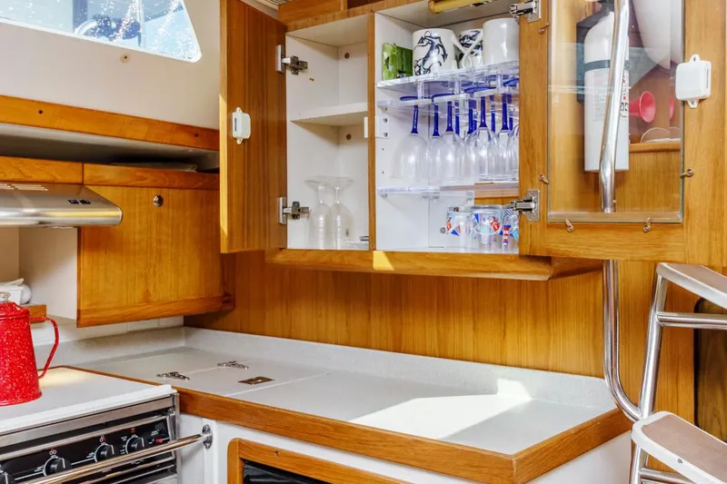 Blue Moon Yacht Photos Pics Interior of 2004 Catalina 400 MkII yacht kitchen with wooden cabinets and glassware.