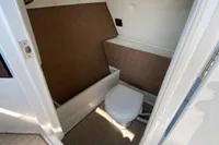 2020 Cobalt R7 Surf boat interior bathroom with compact toilet and beige walls.