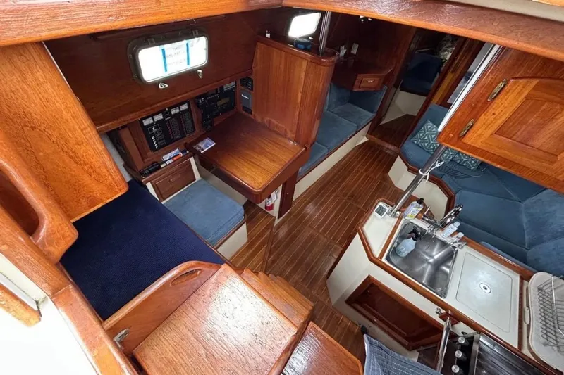 Kai Mana Yacht Photos Pics Interior of 1990 Pacific Seacraft PSC 37 sailboat with wood finish and compact kitchen.