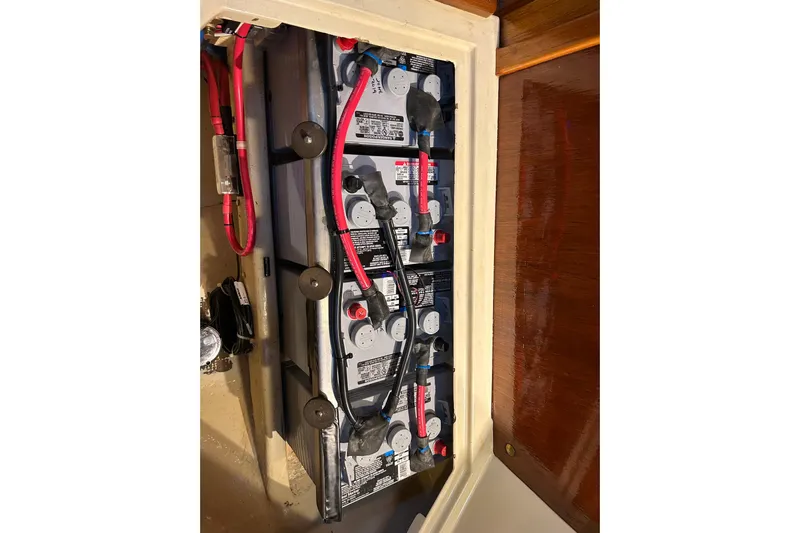 Kai Mana Yacht Photos Pics Battery compartment of a 1990 Pacific Seacraft PSC 37 sailboat with red and black cables.