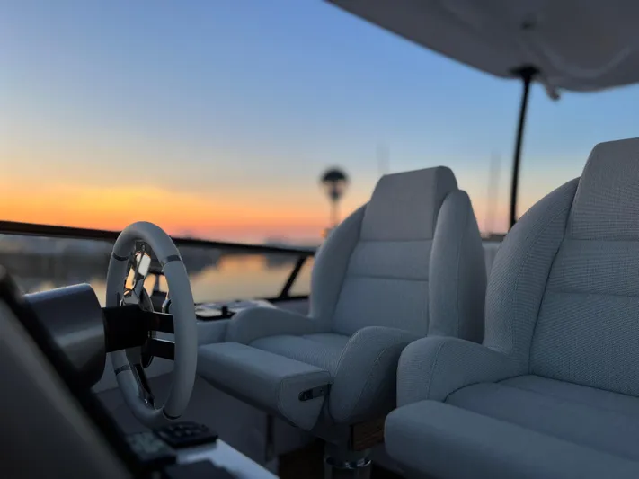  Yacht Photos Pics Pilot seats and steering wheel of 2023 Azimut Magellano 66 yacht at sunset.