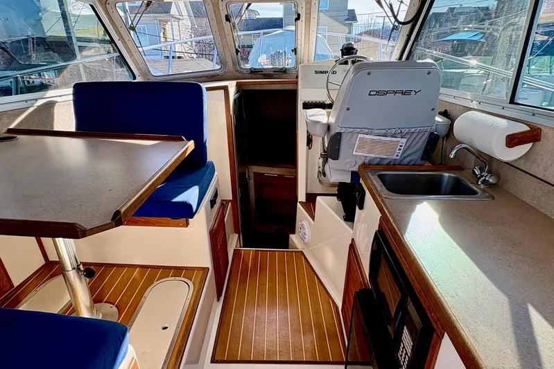  Yacht Photos Pics Interior of 2017 Osprey 30 Fisherman boat with seating, table, and kitchenette.